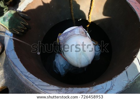 Confined space entry by a worker who wear white chemical suit. Royalty-Free Stock Photo #726458953