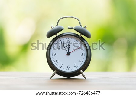 Retro alarm clock with five minutes to twelve o'clock.