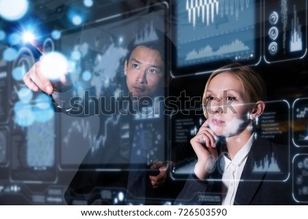 Two business persons in front of futuristic display. Graphical User Interface(GUI). Head up Display(HUD). Internet of things. Royalty-Free Stock Photo #726503590