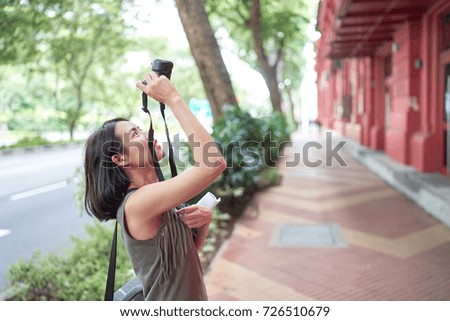Tourist woman taking photo of the top of building at Singapore