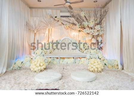 Malay bride and groom pelamin for their wedding day reception. Decorated with soft colours and flowers to give a soothing and calming feel. It is also designed to give emphasis to the newlyweds.  Royalty-Free Stock Photo #726522142