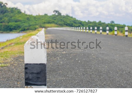 Black and white mileposts on a road near river