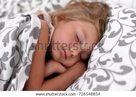 A peaceful photo of a little girl sleeping in a bed 