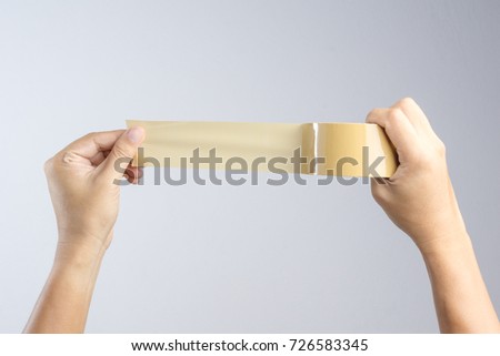 Hand holding brown packaging tape roll on white background Royalty-Free Stock Photo #726583345