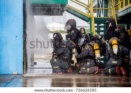 Firemen using water from hose for fire fighting at firefight training of insurance group. Firefighter wearing a fire suit for safety under the danger case.Firefighters training,