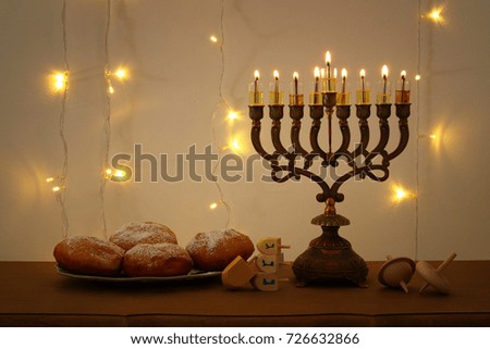 Low key image of jewish holiday Hanukkah background with traditional spinnig top, menorah (traditional candelabra) and burning candles
