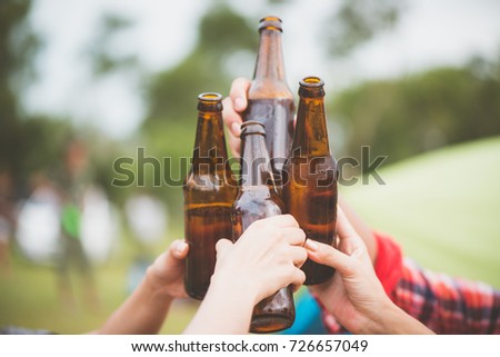 Bottles of beer.Group of friends enjoying party.people are drinking beer and laughing . The guy plays the guitar. Everyone has a great mood. Summer time. Vintage effect style pictures.