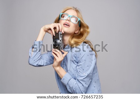 woman young photographer with glasses holds a retro camera on a gray background                               