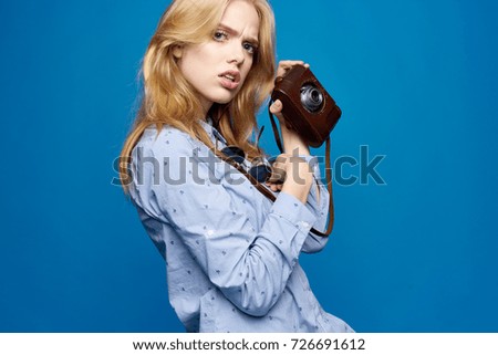 woman photographer holds a cover from the camera on a blue background                               