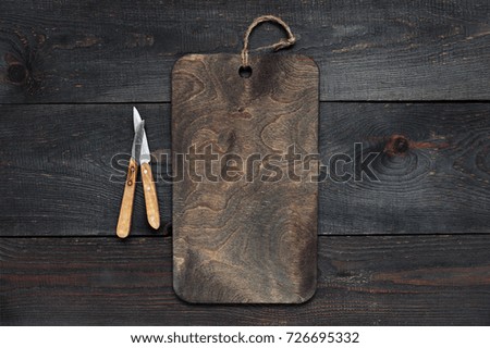 Wooden background with empty board and knives