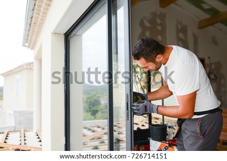 handsome young man installing bay window in a new house construction site