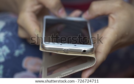 A girl is holding a phone and writing an SMS