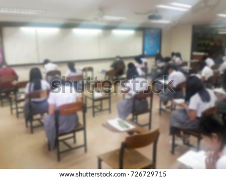 Blur background university students writing answer doing exam in classroom, view from back of the class