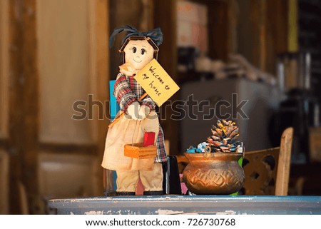 Handmade doll with Welcome to my home sign standing on a windowsill