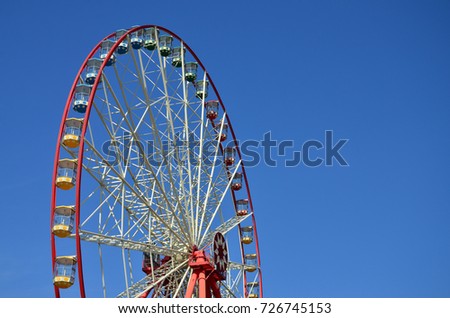 Big and modern multicolour ferris wheel on clean blue sky background
