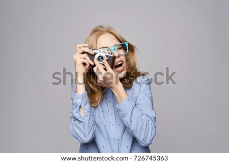woman photographer in glasses takes pictures at the camera on a gray background                               