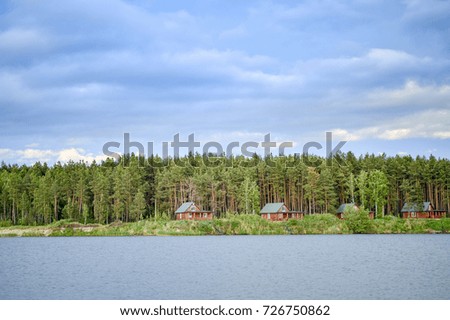 the houses on the lake in a pine forest at sunset.