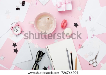 Fashion pink woman workplace background. Coffee, macaron, office supply, gift and clean notebook on pastel desk top view for blogging. Flat lay style. Beautiful morning breakfast.