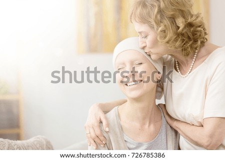 Elderly woman kissing happy cancer survivor's temple, comforting her friend Royalty-Free Stock Photo #726785386