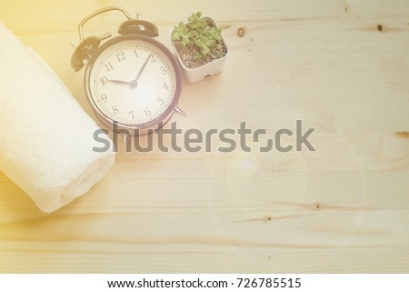 top view. equipment include retro clock, white towel and plant in vase placed on wooden floor with sunshine on top are background. this image for healthy, sport, exercise, hobby, texture concept