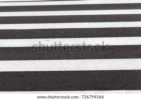white markings on a black asphalt road from a pedestrian crossing. photo closeup in rainy cloudy weather