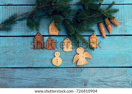 christmas background / figures of houses, snowman angel and spruce branch  on the blue  wooden background
