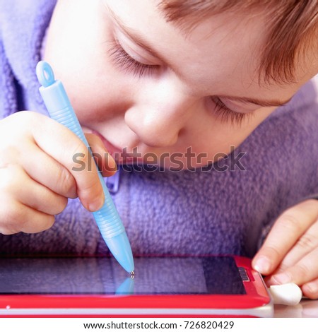 Baby girl drawing on the  graphics tablet. The young art and web designer. (Humorous picture)