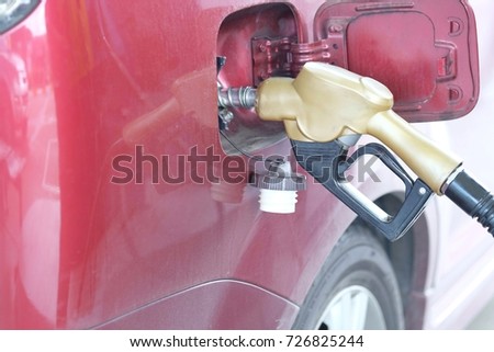 The red car is refueling at the petrol station with gold oil dispenser.