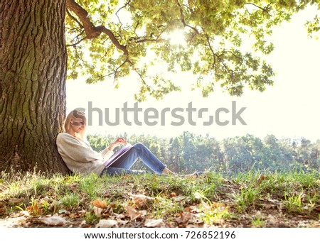 girl sits under a golden autumn tree