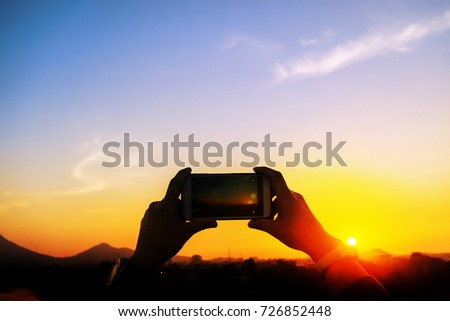 Hands using smartphone take photo at sunset