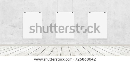 Tree white blank posters with binders in interior with concrete wall and wooden floor