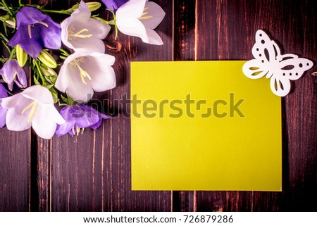 green mockup card with copy space and butterfly and spring flowers on wooden background. sale, greeting and celebration card concept.