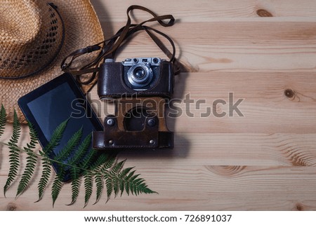 Vacation accessories closeup on wooden background/Accessories for travelers. Camera, hat, tablet and fern on the wooden background. Top view with copy space