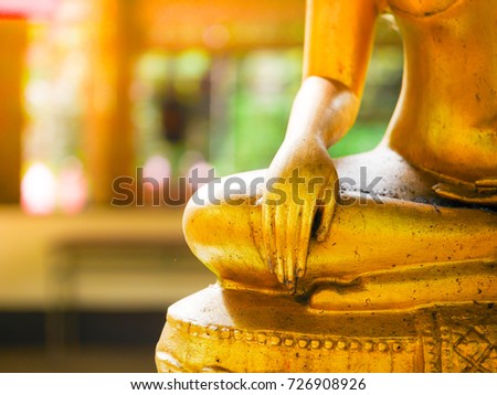 hand of golden buddha statue, hand on knee and sitting cross-legged. 