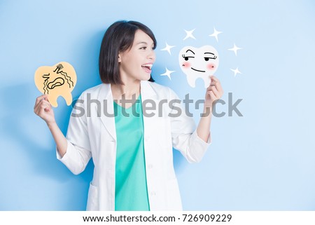 woman dentist take decay and health tooth board on the blue background