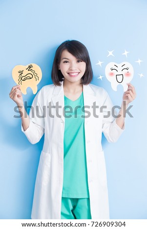 woman dentist take decay and health tooth board on the blue background