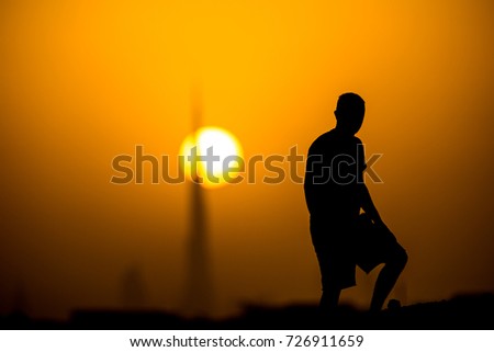 silhouette of man on the background of the tallest building at sunset with a huge sun