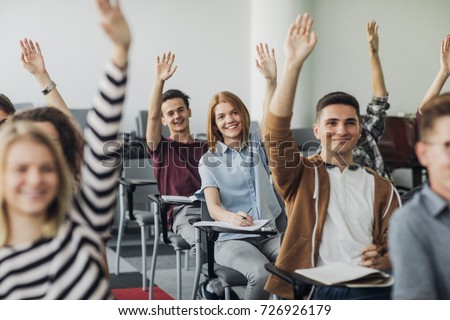 Group of highs school students sitting at classroom and holding hand up. Royalty-Free Stock Photo #726926179