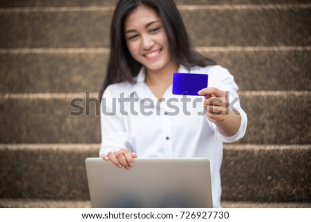 A cute girl holding credit card and using laptop for online shopping at home.