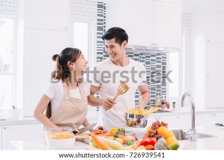 Couple making salad healthy food together and cooking pasta in the kitchen at home. Couple in kitchen concept.