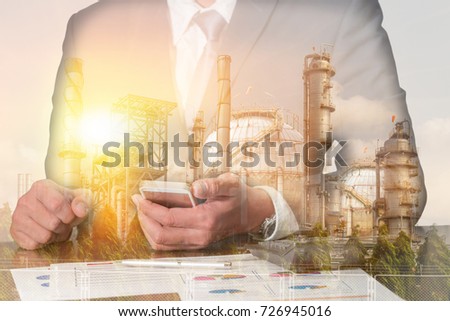 Double exposure of businessman working with smartphone, oil fuel, Electric generating factory or plant with sunset as business, technology, communication, industrial and energy concept.