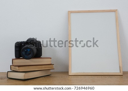 Picture frame, books and digital camera arranged on table