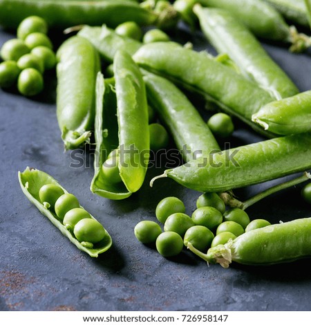 Young organic green pea pods and peas over blue gray texture metal background. Close up with space. Harvest, healthy eating. Square image