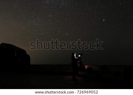 Unidentified tourist with professional camera taking picture on beautiful night stars