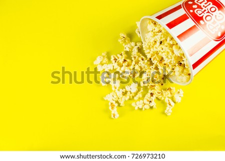 Popcorn in red and white cardboard box or  striped paper cup isolated on yellow background.