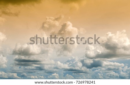 The two-color sky is golden and the colors alternate with white clouds.