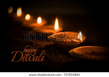 Happy Diwali greeting card design using Beautiful Lit Diya OR Clay oil lamps. Selective focus