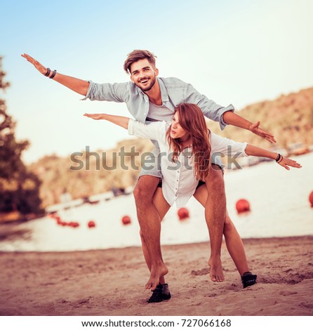 Picture of a joyful couple doing piggyback on the beach.Crazy in love.