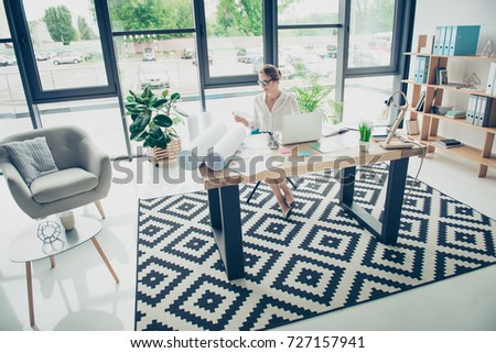 Visual art design, tone, remodeling, web, concept. Creative work place of light modern design, nice interior, plants, huge windows, shelves with folders, armchair, lady is doing paper work