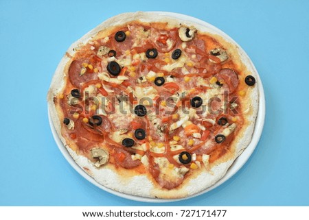 homemade pizza with olives and cheese on a blue background